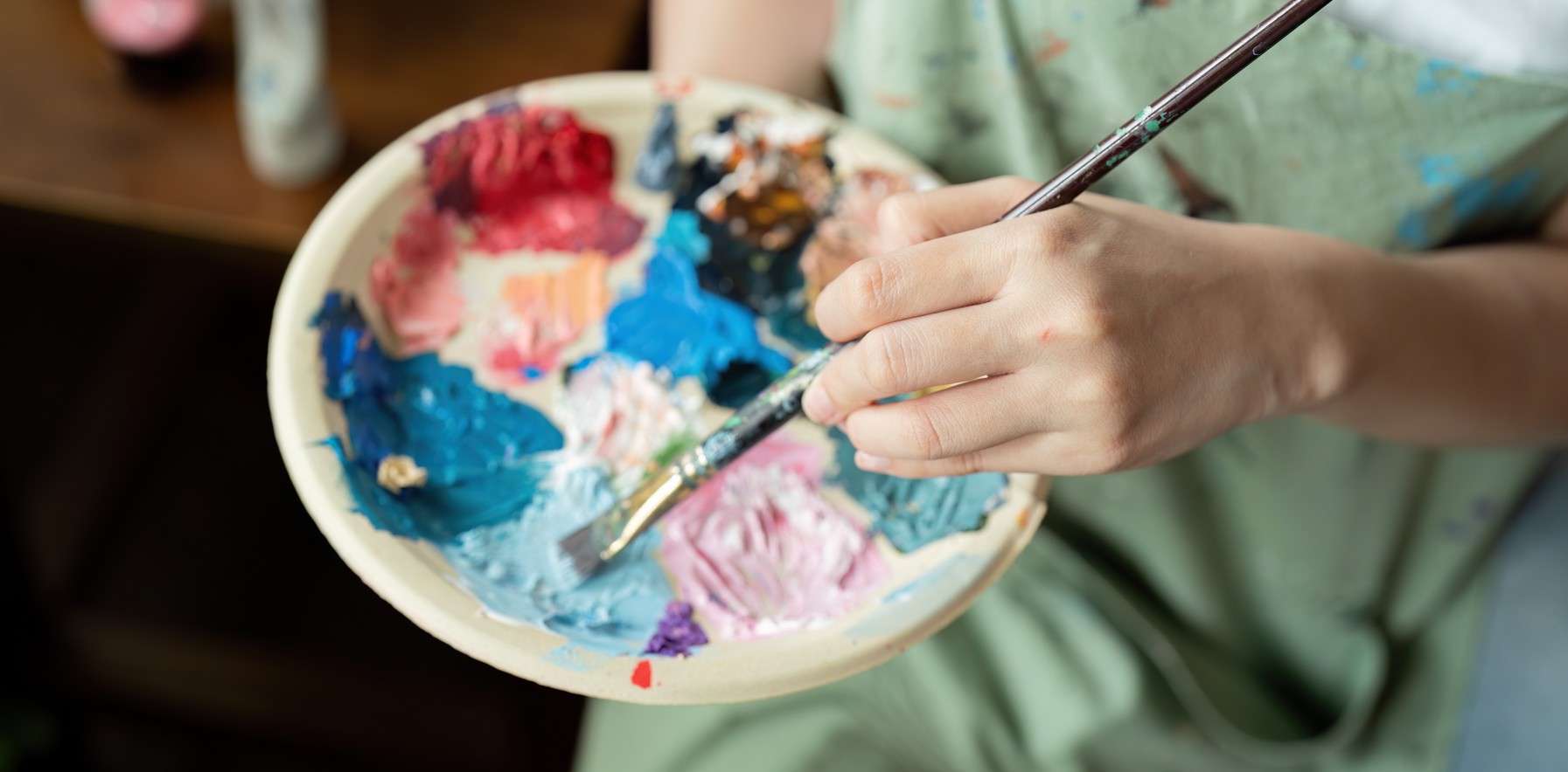 Estudiante mezclando pinturas en una paleta como parte del proceso artístico en la Licenciatura en Artes Visuales.