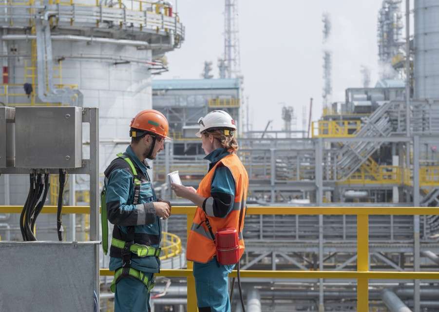Dos ingenieros o supervisores en un entorno industrial, revisando planes para la gestión de procesos logísticos y la optimización de la cadena de suministro en plantas de producción.