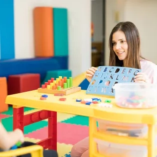 Docente en licenciatura en Educación Especial trabajando con niño en actividades de estimulación cognitiva.