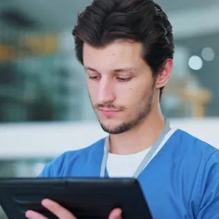 Profesional de la salud utilizando una tablet, representando la implementación de la telesalud y la telemedicina para la atención remota y el acceso a la información del paciente.