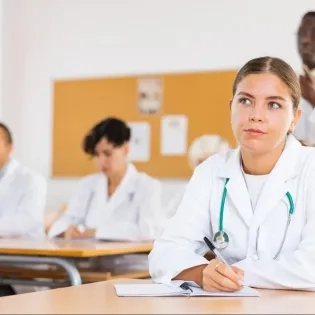 Estudiantes de la especialización en auditoría médica virtual tomando notas en clase sobre control y calidad en salud.