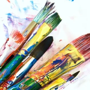 Pinceles con pintura de colores vivos utilizados en procesos creativos de la Licenciatura en Artes Visuales.