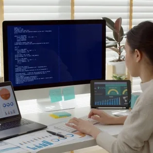 Vista trasera de una estudiante de MBA en su escritorio, rodeada de análisis de datos y gráficos empresariales, representando las competencias clave qué aprenderás en un MBA."