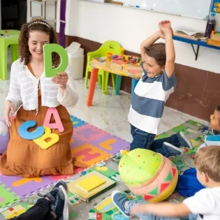 Profesora enseñando el abecedario a niños para prevenir dificultades de aprendizaje