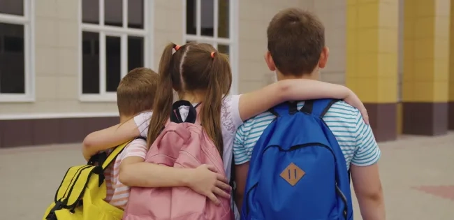 Niños caminando juntos hacia el colegio, símbolo del acompañamiento y las estrategias para el desarrollo integral en la infancia.
