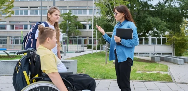 Docente de la especialización en infancia y adolescencia dialogando con estudiantes en un entorno de educación inclusiva dentro del sistema escolar.