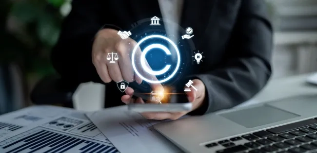 Mano interactuando con iconos legales digitales y de copyright sobre un teléfono, representando la regulación estatal y la propiedad intelectual, temas centrales para entender qué es el Derecho Administrativo. Incluye balanza de justicia y mazo.