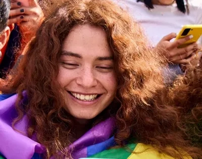 Grupo de jóvenes usando teléfonos móviles, sonriendo y con elementos que sugieren diversidad y conexión social, representando la vida digital y sus desafíos de salud mental.