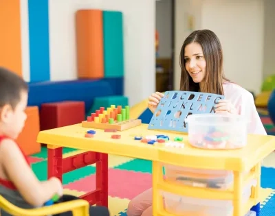 Docente en licenciatura en Educación Especial trabajando con niño en actividades de estimulación cognitiva.