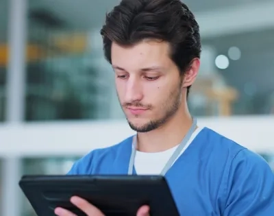 Profesional de la salud utilizando una tablet, representando la implementación de la telesalud y la telemedicina para la atención remota y el acceso a la información del paciente.