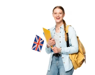 Estudiante feliz con una mochila y carpetas, sosteniendo una bandera del Reino Unido, simbolizando el aprendizaje de lenguas extranjeras y la inmersión cultural.