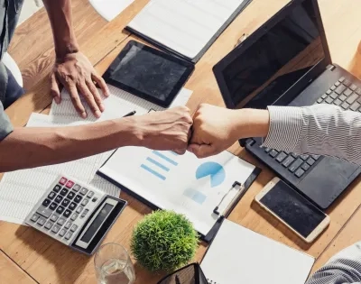 os profesionales celebran con un choque de puños el éxito en la eficiencia empresarial mediante el análisis de datos, enfoque de la Ingeniería Industrial Ibero.