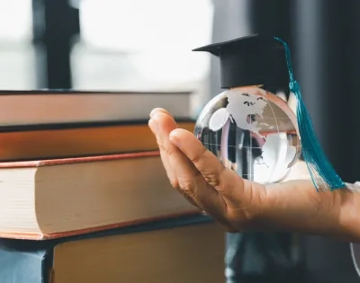 Mano sosteniendo un globo terráqueo con birrete simbolizando el impacto global del postgrado en educación y la mejora del salario docente en el escalafón nacional.