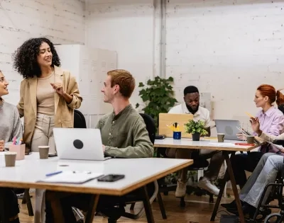 Equipo multidisciplinario en una sesión de planeación comunitaria, destacando la comunicación asertiva y la empatía como habilidades de un trabajador social.