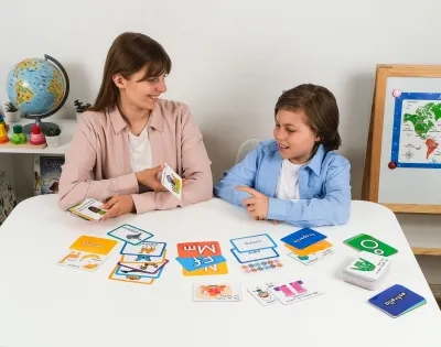 Maestra de humanidades y lengua castellana realizando actividades de lectoescritura con un niño usando tarjetas didácticas para fortalecer el aprendizaje del idioma.