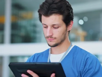 Profesional de la salud utilizando una tablet, representando la implementación de la telesalud y la telemedicina para la atención remota y el acceso a la información del paciente.