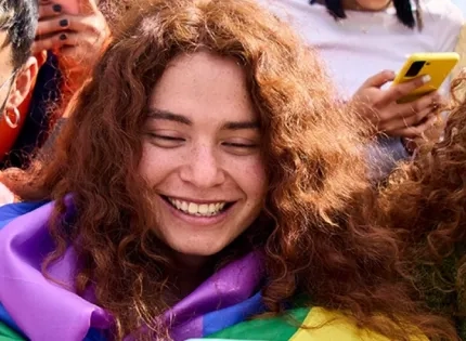 Grupo de jóvenes usando teléfonos móviles, sonriendo y con elementos que sugieren diversidad y conexión social, representando la vida digital y sus desafíos de salud mental.