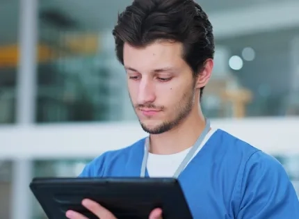 Profesional de la salud utilizando una tablet, representando la implementación de la telesalud y la telemedicina para la atención remota y el acceso a la información del paciente.
