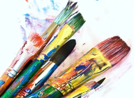 Pinceles con pintura de colores vivos utilizados en procesos creativos de la Licenciatura en Artes Visuales.