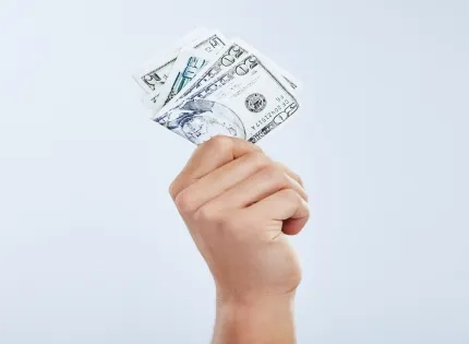 Mano sosteniendo un fajo de dólares, representando el pago de la prima de servicios en el programa de contaduría pública.