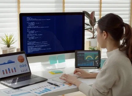 Vista trasera de una estudiante de MBA en su escritorio, rodeada de análisis de datos y gráficos empresariales, representando las competencias clave qué aprenderás en un MBA."