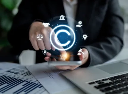 Mano interactuando con iconos legales digitales y de copyright sobre un teléfono, representando la regulación estatal y la propiedad intelectual, temas centrales para entender qué es el Derecho Administrativo. Incluye balanza de justicia y mazo.