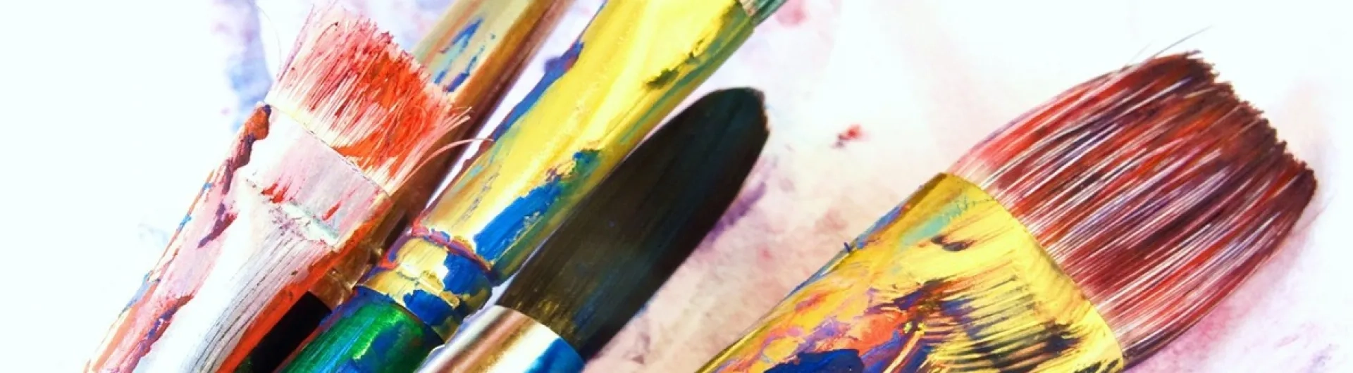 Pinceles con pintura de colores vivos utilizados en procesos creativos de la Licenciatura en Artes Visuales.