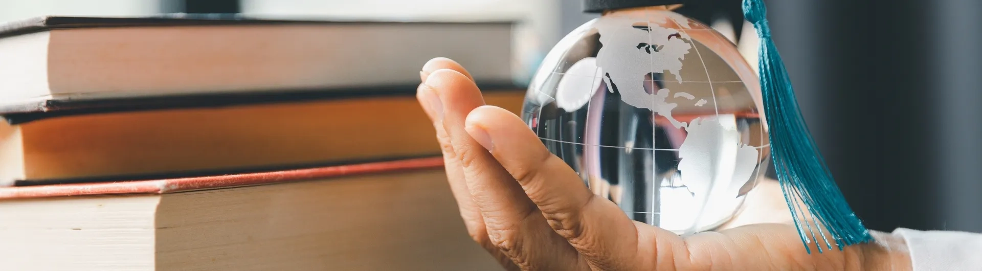 Mano sosteniendo un globo terráqueo con birrete simbolizando el impacto global del postgrado en educación y la mejora del salario docente en el escalafón nacional.