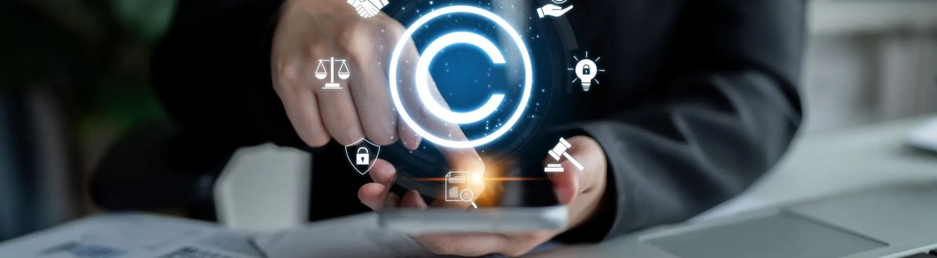 Mano interactuando con iconos legales digitales y de copyright sobre un teléfono, representando la regulación estatal y la propiedad intelectual, temas centrales para entender qué es el Derecho Administrativo. Incluye balanza de justicia y mazo.