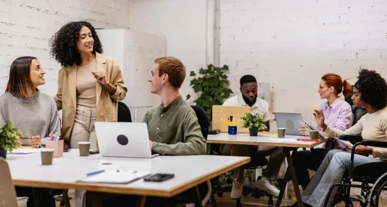 Equipo multidisciplinario en una sesión de planeación comunitaria, destacando la comunicación asertiva y la empatía como habilidades de un trabajador social.
