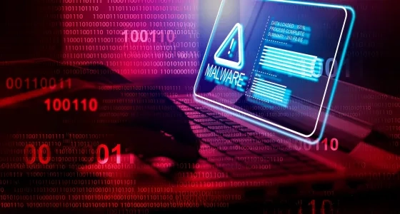 Alerta digital de malware parpadeando sobre el teclado de una computadora portátil con fondo de datos binarios, ilustrando la vulnerabilidad informática y soluciones en ciberseguridad para pequeñas empresas